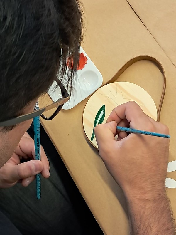 Participante pintando uma peça de madeira com aquarela em oficina do ManualMente
